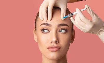 woman's forehead about to be injected with needle